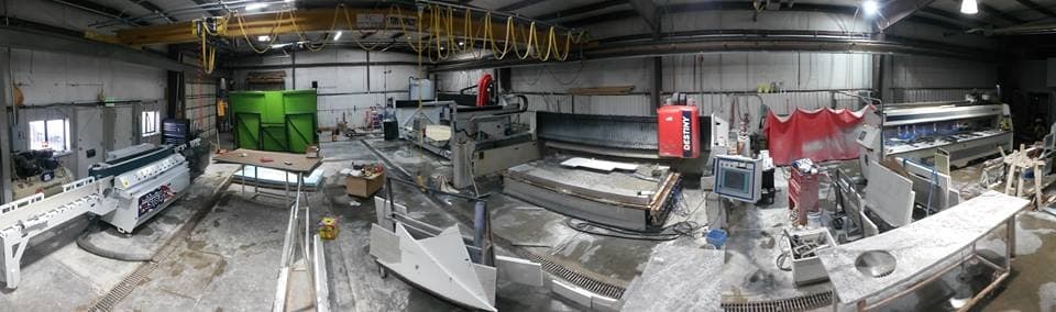 The Stone Concepts fabrication shop floor with slab saws, a CNC bridge and stone slabs